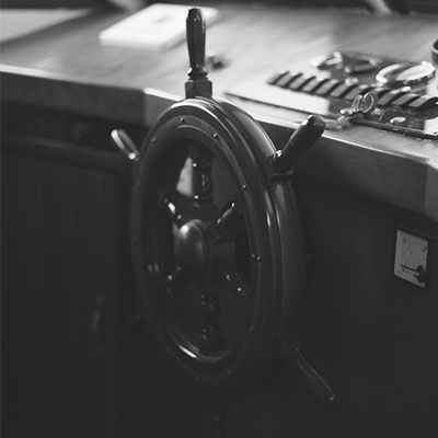 Timón clásico de barco montado en el puente de mando, detalle en blanco y negro de la rueda y controles